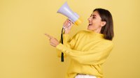 young-woman-yellow-warm-sweater-with-megaphone-speaker-screaming-left-pointing-index-finger (1).jpg