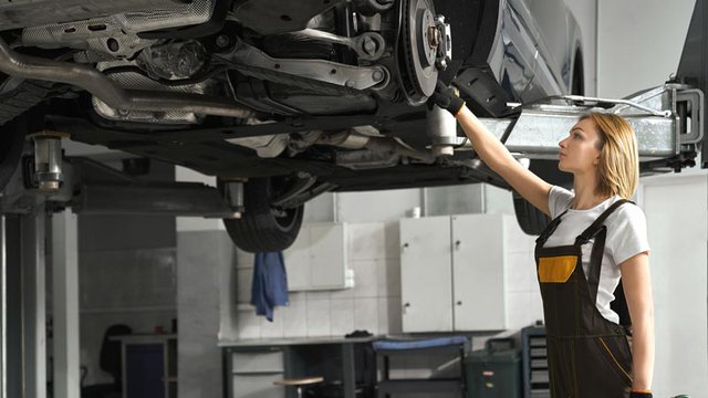 woman-coveralls-fixing-brake-discs-lifted-car.jpg